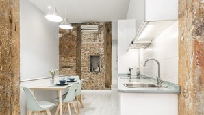 A modern kitchen with a brick wall, a dining area with light-colored chairs, and a built-in sink.