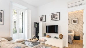Una sala moderna con sofá, televisor y comedor.