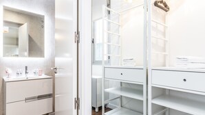 Un baño moderno con tocador blanco, un espejo y un mueble-estante empotrado.