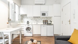 Una cocina compacta con lavadora, microondas y un comedor con mesa y sillas.