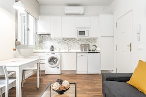 Una cocina compacta con lavadora, microondas y un comedor con mesa y sillas.