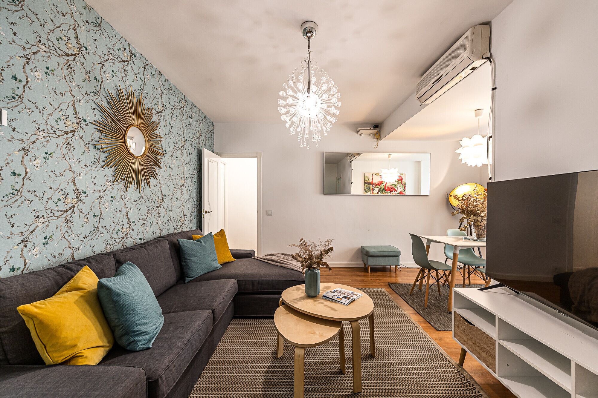 Ein modernes Wohnzimmer mit einem Ecksofa, einem runden Couchtisch und einem Fernseher.