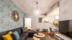 A modern living room with a sectional sofa, a round coffee table, and a TV. - Waou La Latina II - Alquiler Corta Duración (Madrid)