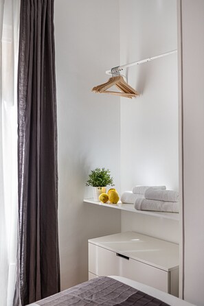 A bathroom with a white sink, a mirror, a towel rack, and a potted plant.