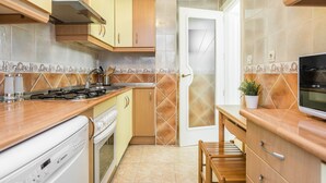 A kitchen with wooden cabinets, a stove, and a microwave. - Waou La Latina II - Alquiler Corta Duración (Madrid)