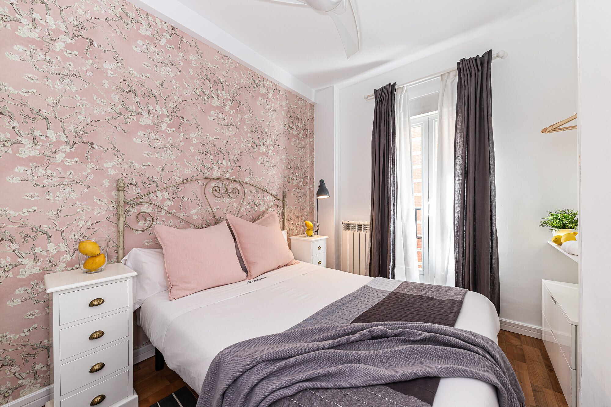 Un dormitorio con cama, mesita de noche, cómoda y ventana con cortinas.