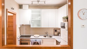 A modern kitchen with white cabinets, a stainless steel sink, a built-in oven, and a dishwasher. - Waou Gran Via I - Alquiler Corta Duración (Madrid)