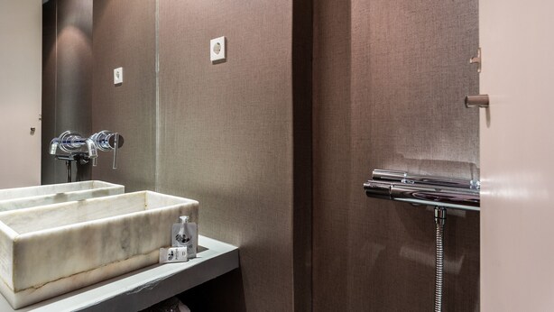 Baño con lavamanos de mármol, espejo y zona de ducha.