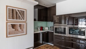 Une cuisine moderne avec des meubles de couleur sombre, des appareils en acier inoxydable et des tableaux encadrés accrochés au mur.