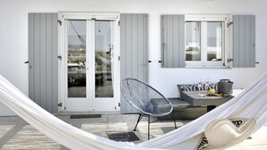 A hammock, a chair, and a table with a bottle and a fruit on it. - Villa Blanca Uno (Mykonos)