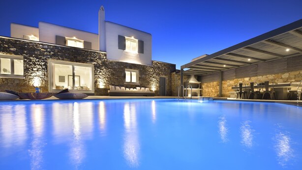 A modern building with a swimming pool, stone walls, and outdoor seating. - Villa Blanca Uno (Mykonos)