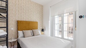 Een hotelkamer met een bed, nachtkastje, lamp, raam met uitzicht en een handdoekrek.