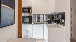Een moderne keuken met witte kastjes, een ingebouwde oven en een grote spiegel boven de gootsteen.