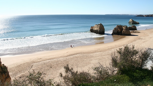 Una playa con grandes formaciones rocosas y una vista despejada del océano.