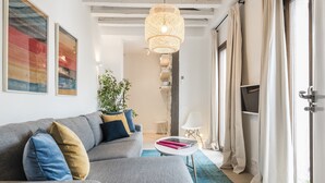 A modern living room with a grey sofa, a round coffee table, and a hanging light fixture. - Waou Sol III - Alquiler de Corta Duración (Madrid)