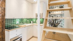 A modern kitchen with white cabinets, green backsplash, and a wooden staircase. - Waou Sol III - Alquiler de Corta Duración (Madrid)