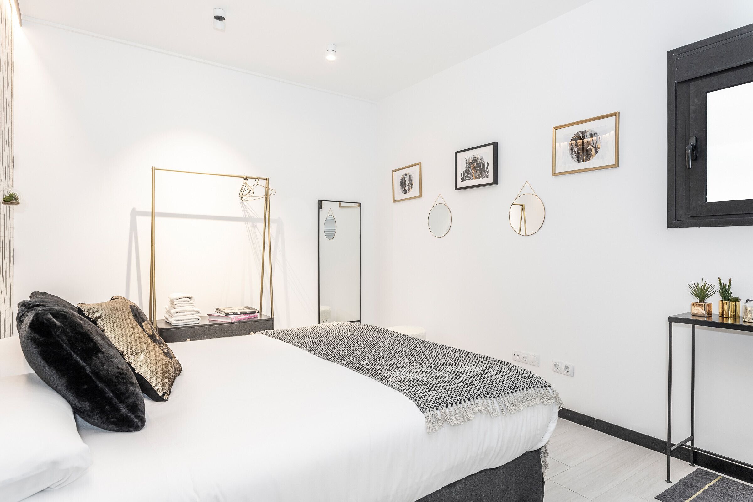 Un dormitorio moderno con una cama grande, una mesita de noche, un espejo y una obra de arte colgada en la pared.