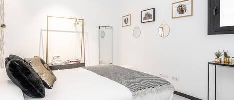 Un dormitorio moderno con una cama grande, una mesita de noche, un espejo y una obra de arte colgada en la pared.