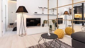 A modern living room with a TV, a floor lamp, and decorative items on shelves. - Waou Malasaña es MIA - Corta Duración (Madrid)