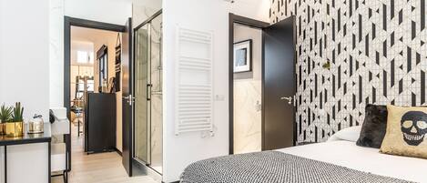 A modern hotel room with a bed, a desk, and a wardrobe.