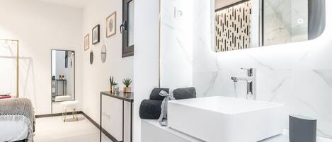 Une salle de bain moderne avec un grand miroir, un lavabo blanc et un porte-serviettes.