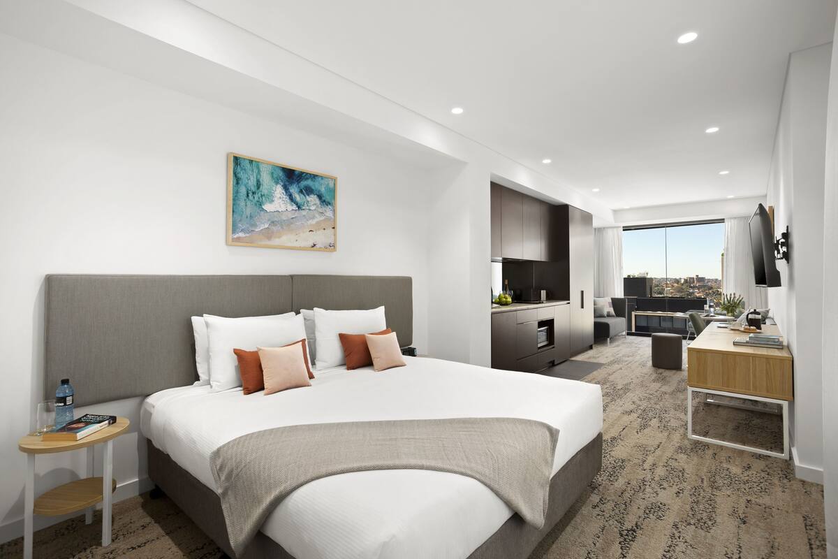 Una habitación de hotel moderna con una cama grande, un escritorio y un televisor.