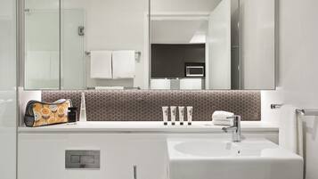 Un bagno moderno con uno specchio grande, un lavandino bianco e un porta asciugamani.