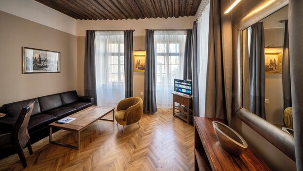 Een moderne woonkamer met een bank, fauteuil, houten salontafel en een flatscreen-televisie.