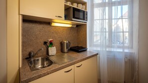 Een keuken met een roestvrijstalen spoelbak, een magnetron en een koffiezetapparaat op het aanrecht.
