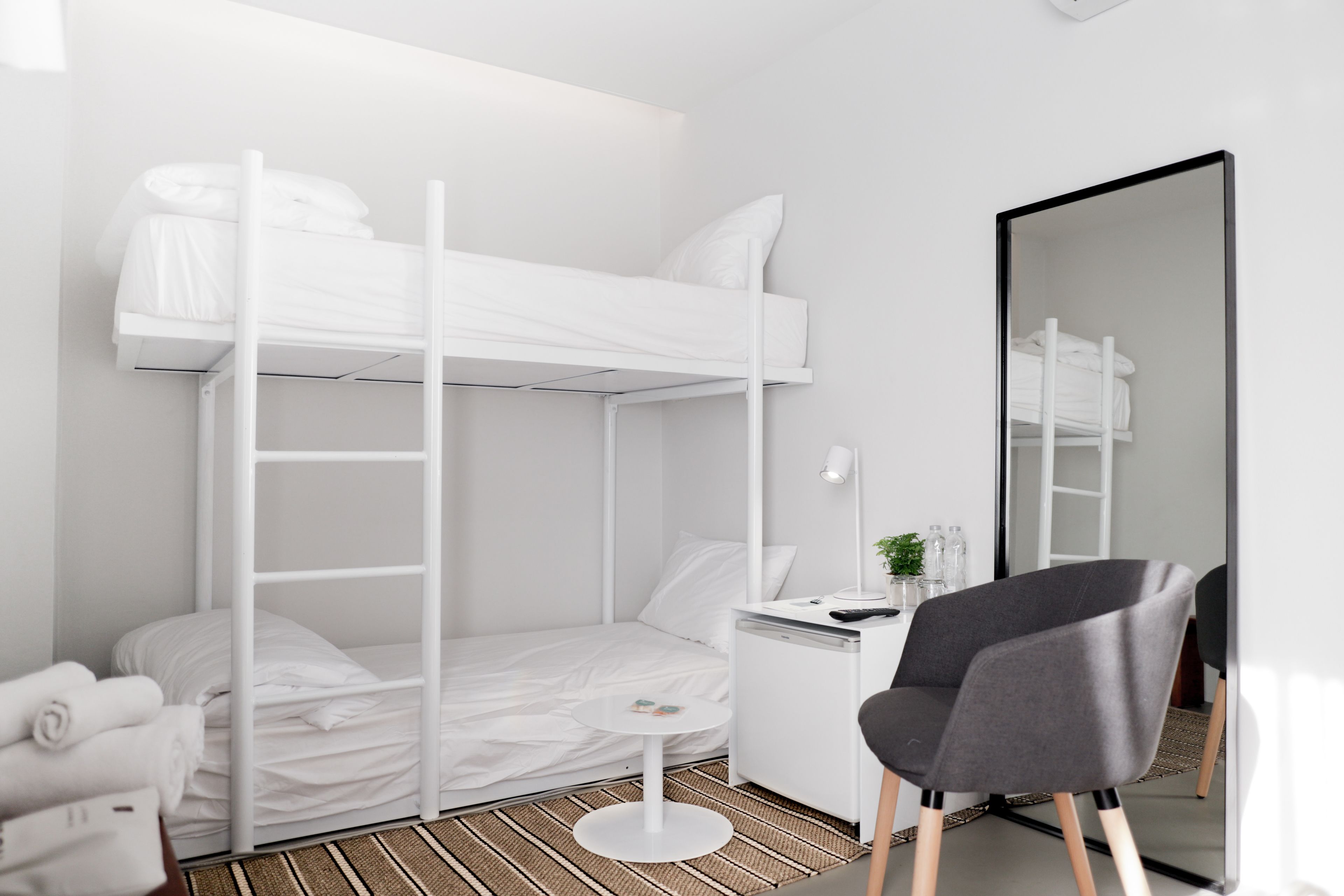 A bunk bed room with a desk, chair, and a mirror.