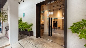 Una entrada de hotel moderna con puertas de cristal, asientos interiores y plantas en macetas.