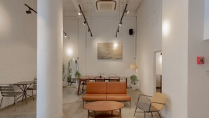 Un interior moderno con una zona de estar central, una mesa de comedor y un cuadro abstracto grande en la pared.