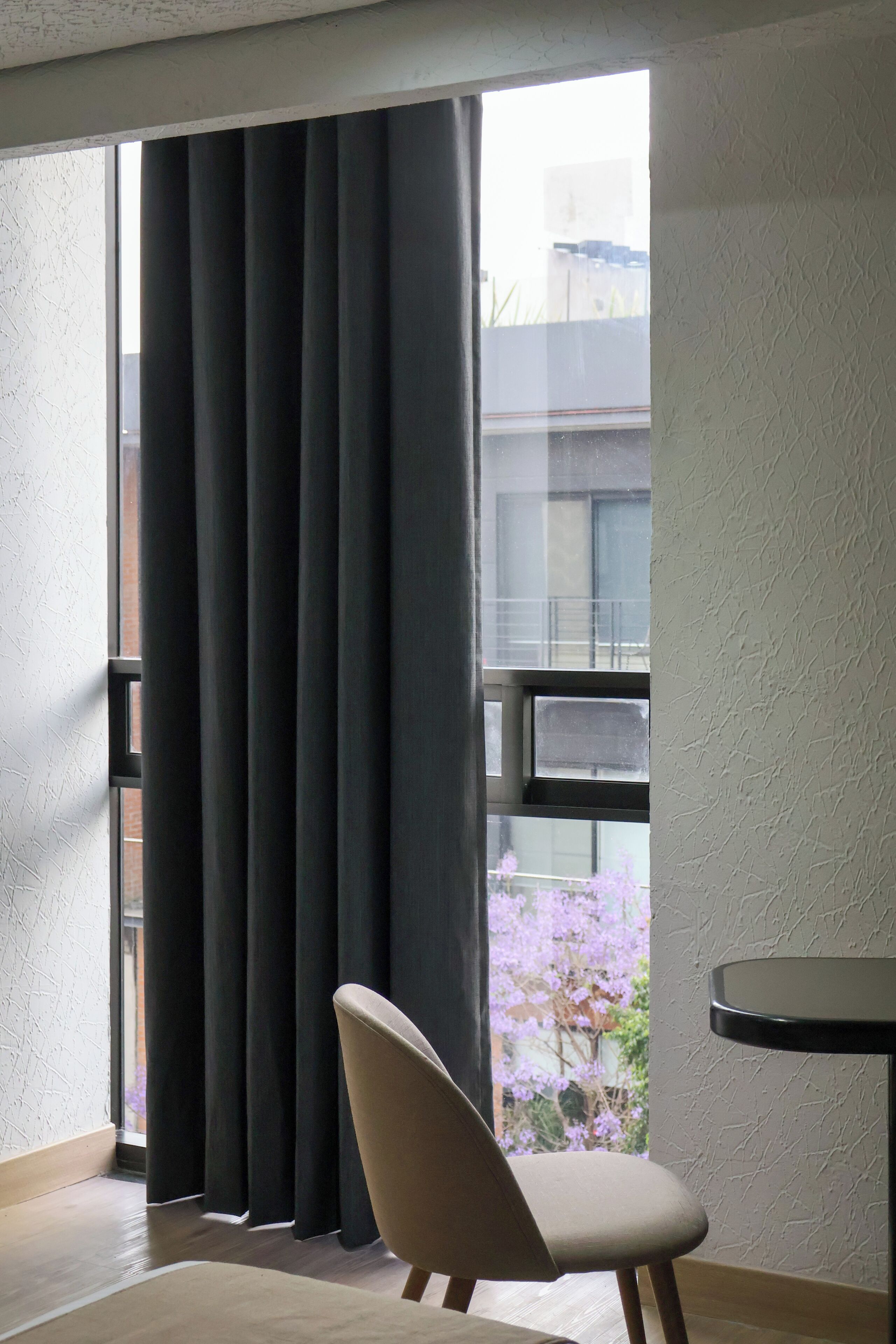 Ein Zimmer mit großem Fenster, einem Sessel und einem kleinen Tisch.