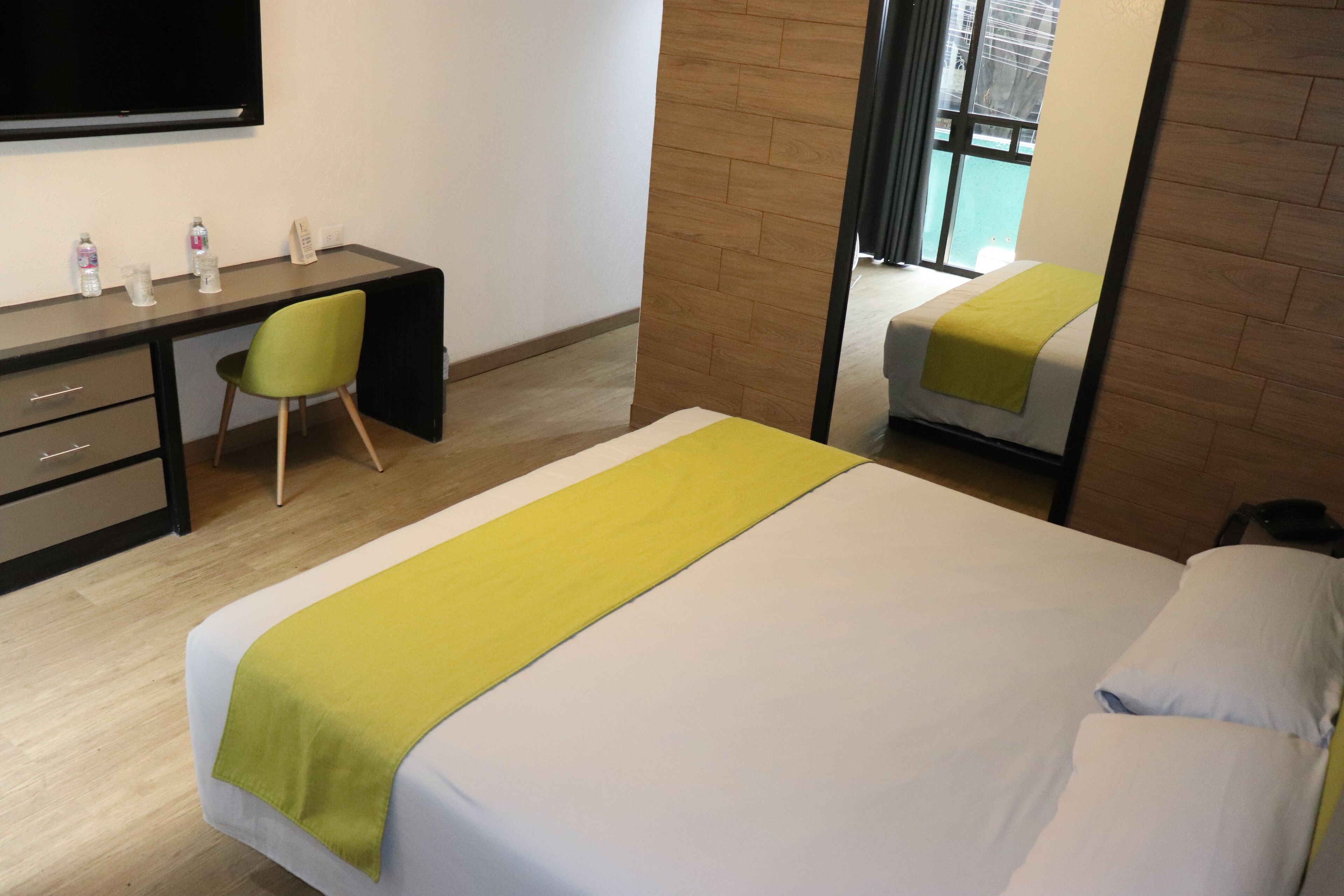 Une chambre d’hôtel équipée d’un lit, d’un bureau, d’une chaise, d’une télévision et d’une fenêtre donnant sur un paysage agréable.