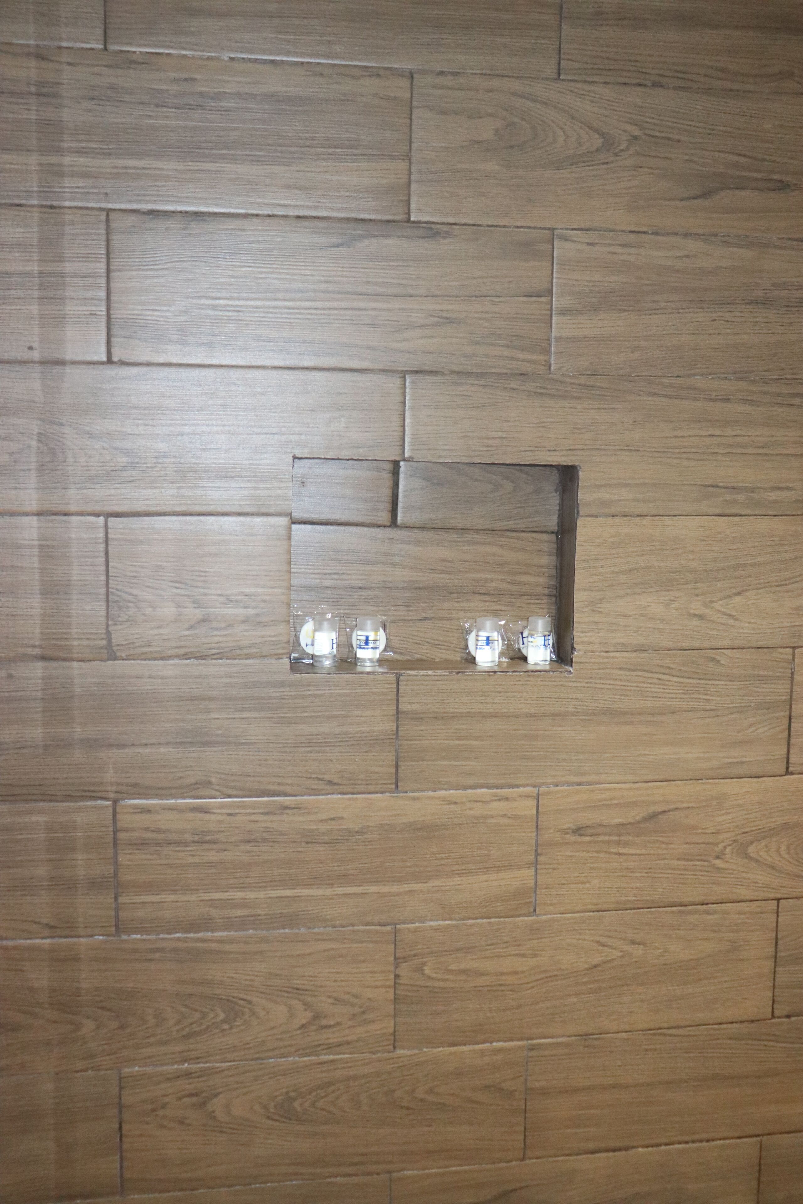 A wooden wall with a recessed shelf holding two glasses.