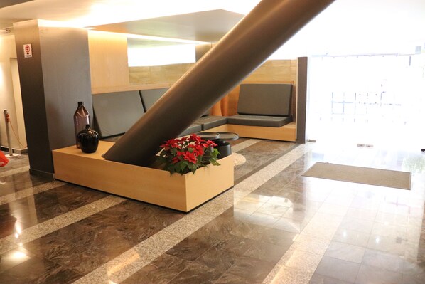 Zona de recepción con un pilar grande, un mostrador de recepción y un espacio para sentarse.