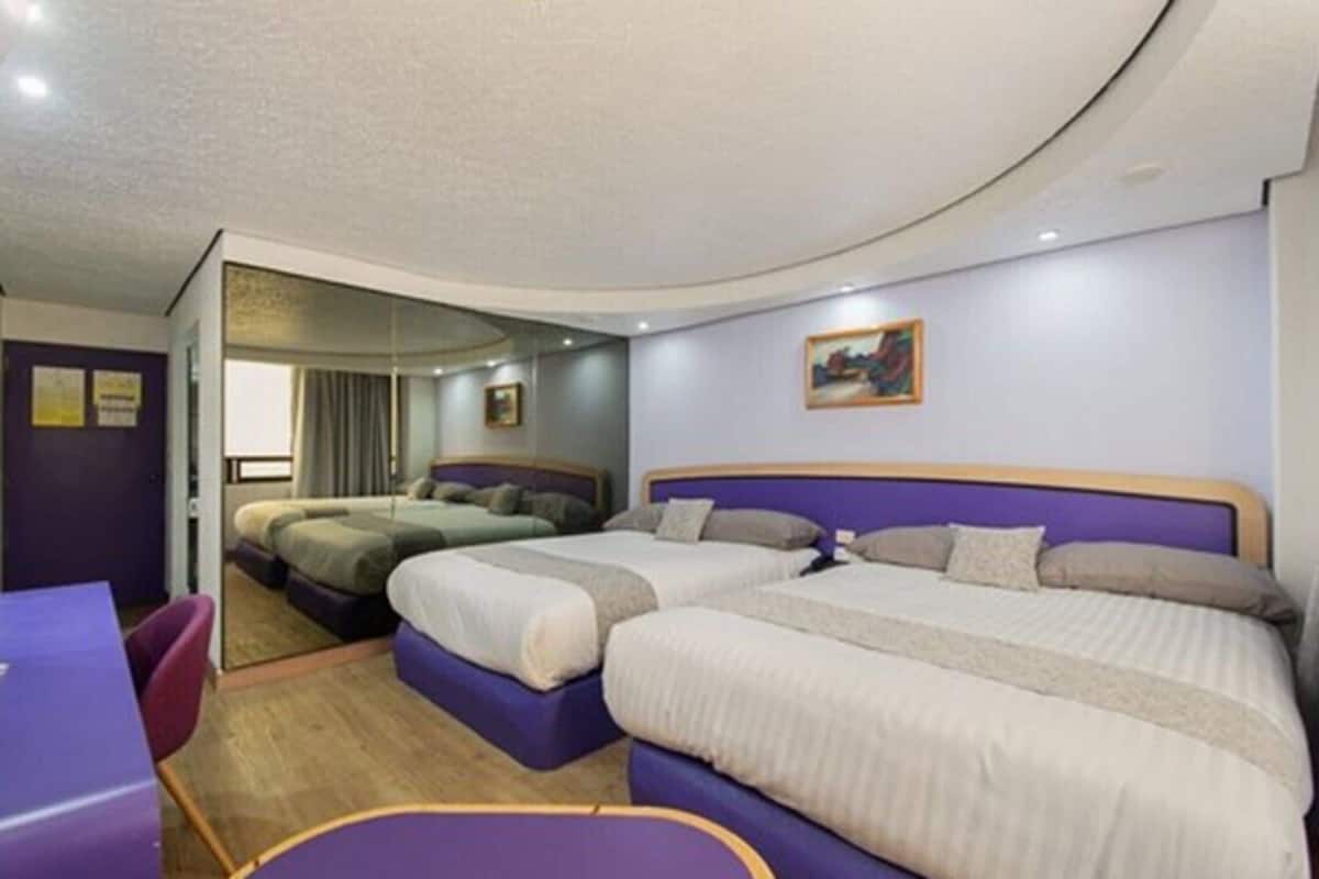 Habitación de hotel con dos camas, un escritorio y vistas a la ciudad.