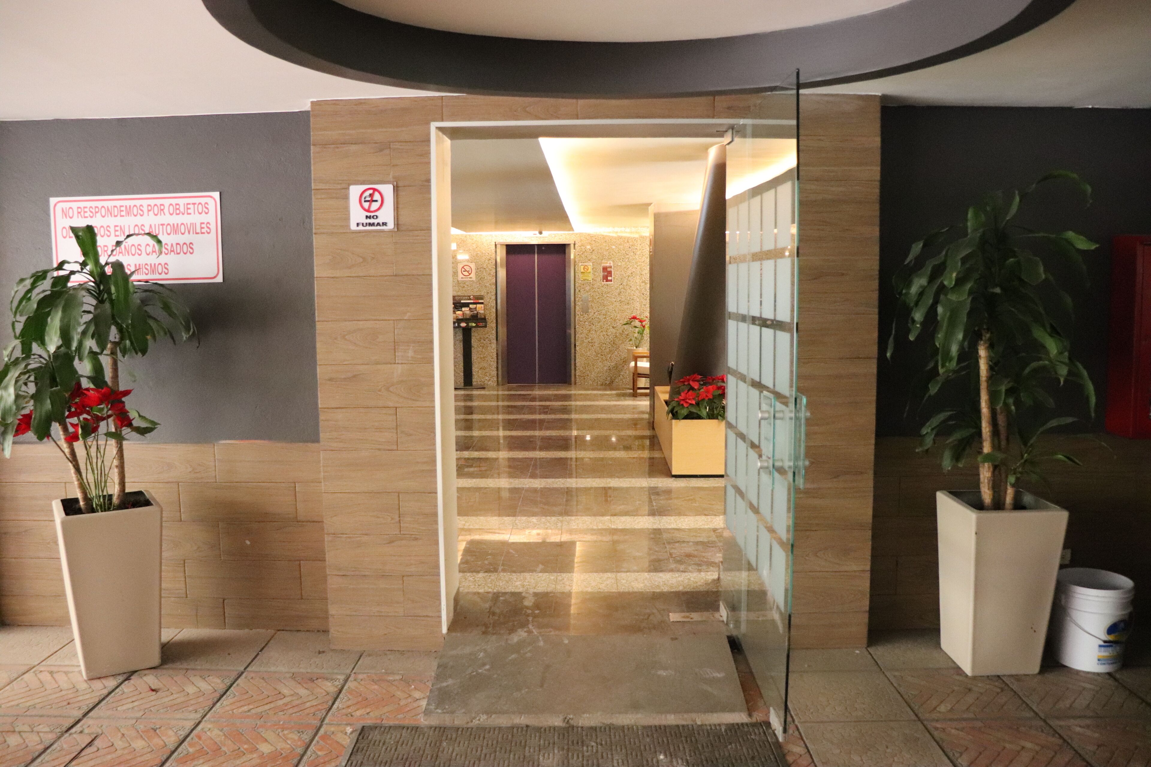 Un vestíbulo de hotel con una recepción, una escalera y plantas en macetas.