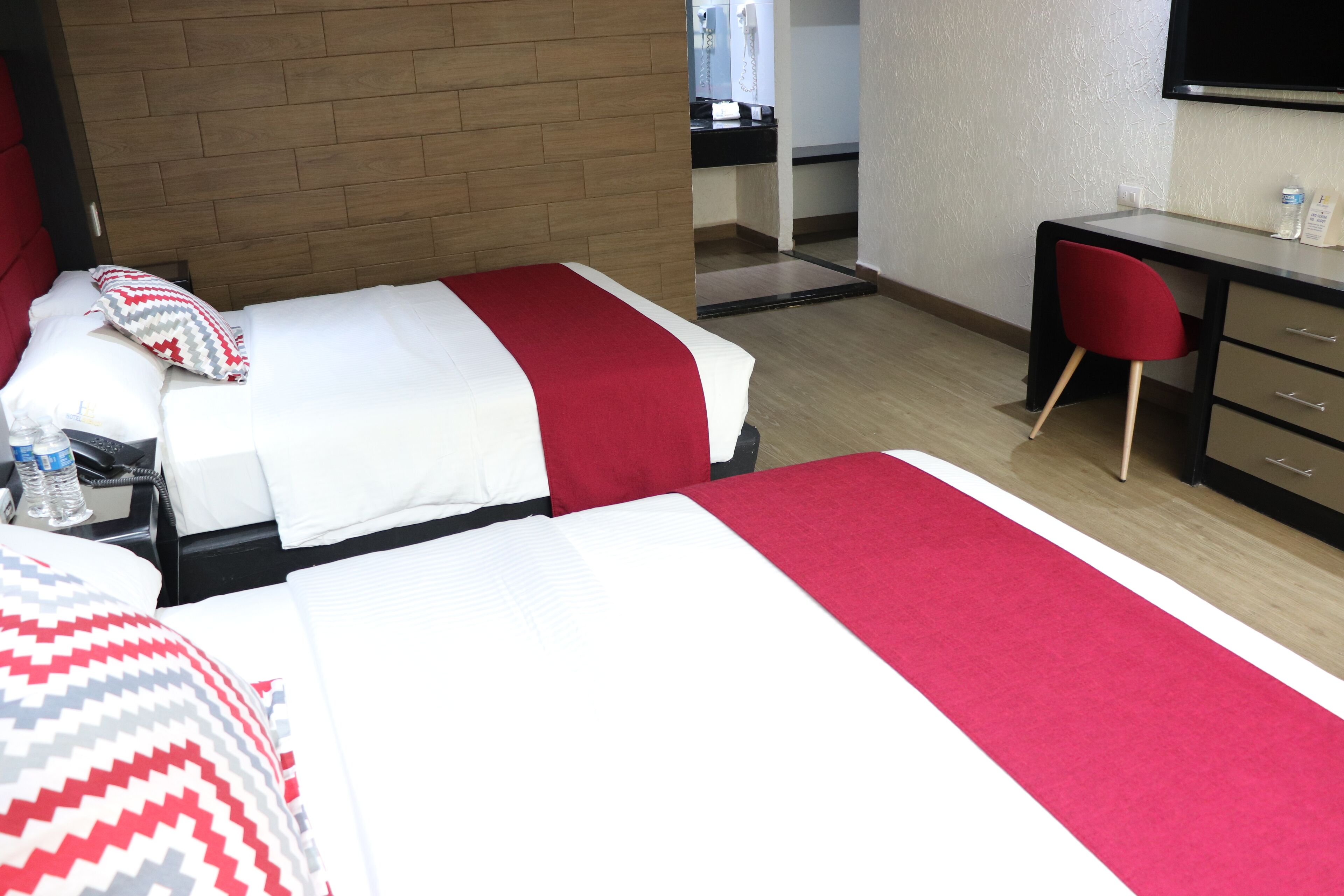 Habitación de hotel con dos camas, un escritorio y una silla.