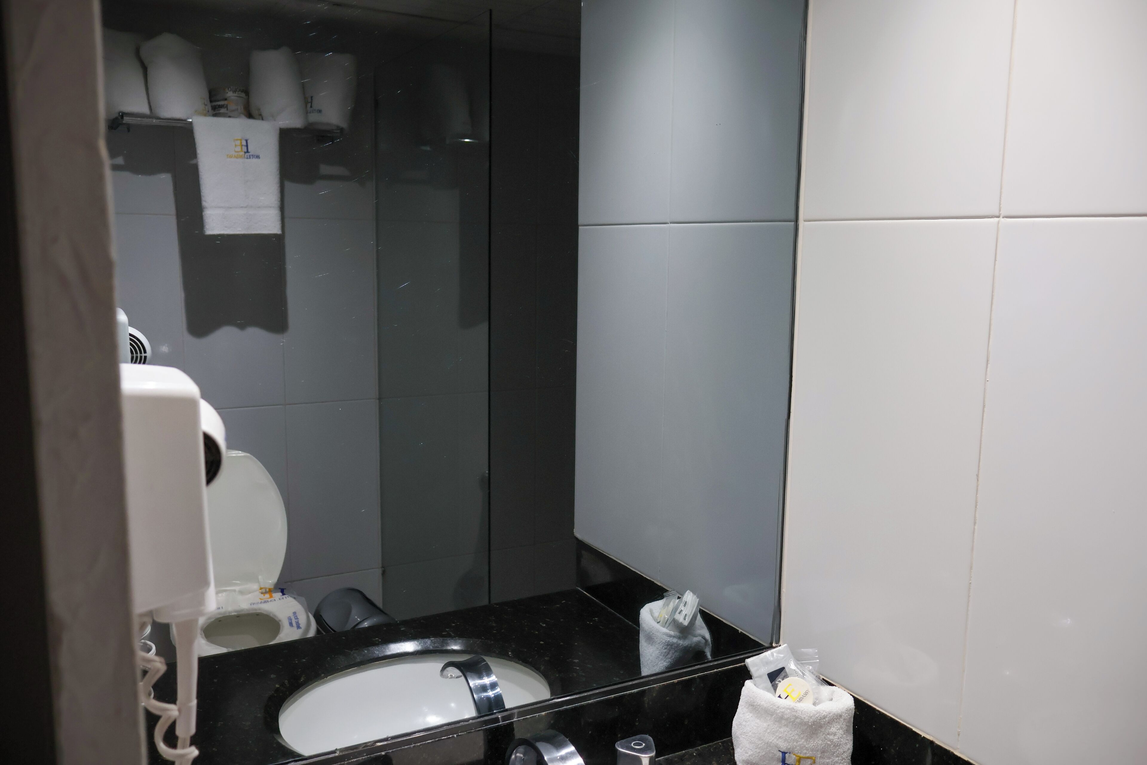 Un baño moderno con lavamanos de mármol negro, inodoro y secamanos.