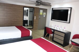 Una habitación de hotel con una cama, un escritorio, una silla, un televisor y un ventilador de techo.