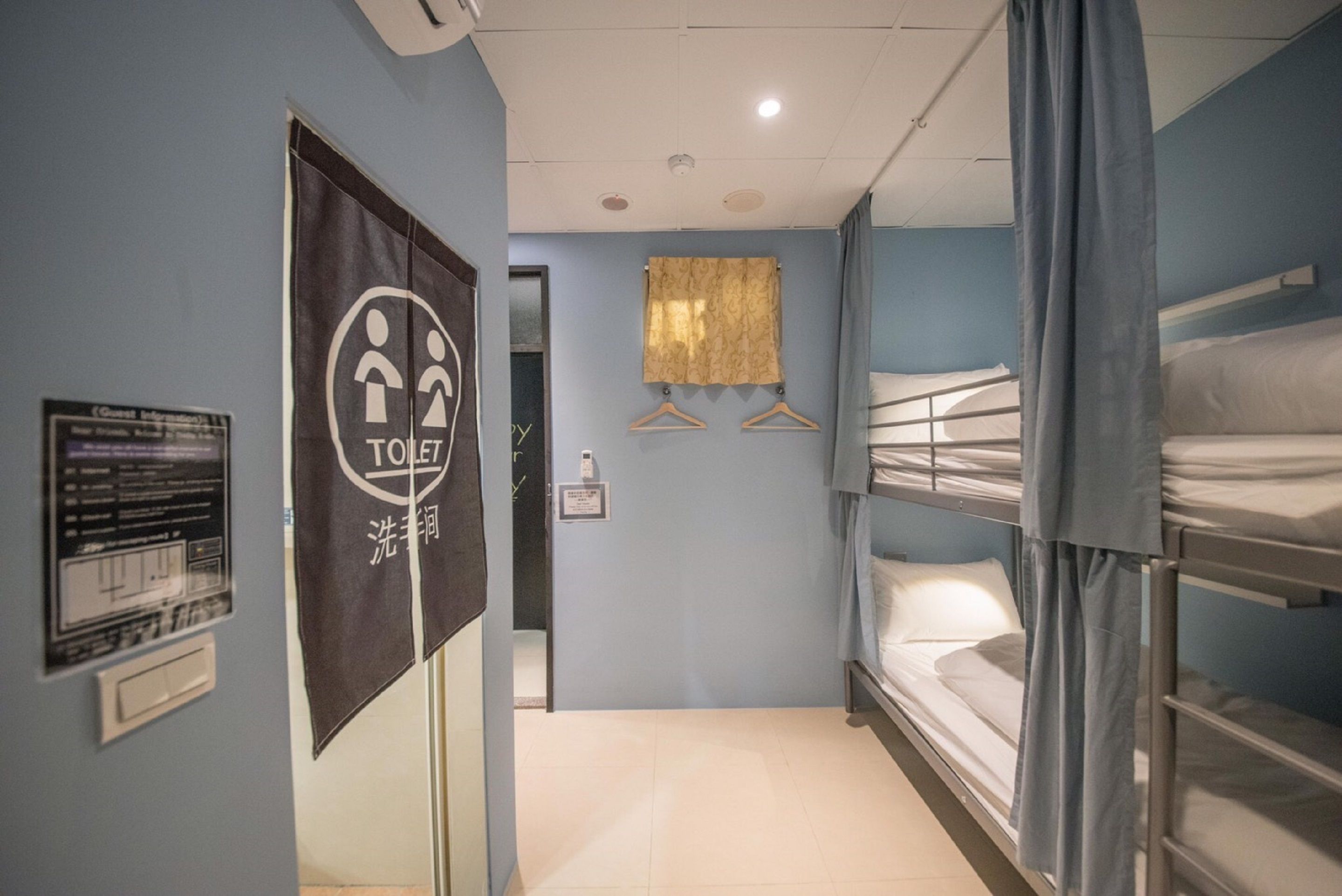 A hotel room with bunk beds, a toilet sign, a shower sign, and a towel hanging on a rack.