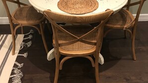 A round dining table with woven placemats, wooden chairs, and a framed menu stand. - Carriage House in Tarrytown - Central Austin, New in 2018 (Austin)