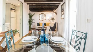 Een eetgedeelte met een glazen tafel voor vier personen, een bank achterin en een houten plafond.