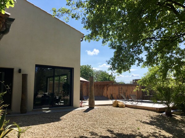 A modern building with large glass windows, a gravel patio, and a wooden fence.