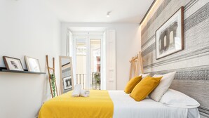 A bedroom with a bed, a yellow throw blanket, and a patterned wall. - Waou Sol es MIA - Corta Duración (Madrid)