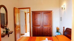 Camera d'albergo con un letto grande, un'armadio in legno, uno specchio e un tavolino con un vaso di fiori.