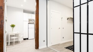 A modern kitchen with white cabinets, a microwave, and a dining area with a table and chairs.