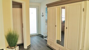 Ein Flur mit großem Kleiderschrank, einer Zimmerpflanze und einer Tür zum Badezimmer.