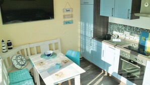 Eine kompakte Küche mit Essbereich, mit einem weißen Tisch, blauen Stühlen und einer kleinen Kücheninsel mit einer Schüssel.